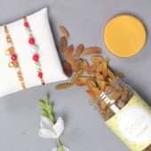 Bead Rakhi N Resins Combo - Set of 2 Designer Rakhi with Complimentary Roli and Chawal and 100gm Raisins in Colorful Floweraura Container