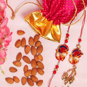 Designer Rakhi N Almond Combo - Set of Bhaiya Bhabhi Peacock Rakhi with Complimentary Roli and Chawal and 100gm Almonds in Pink Potli