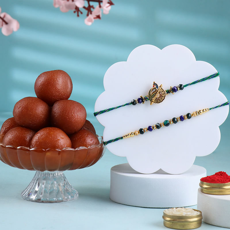Golden Accents Peacock Rakhi Duo With Gulab Jamun