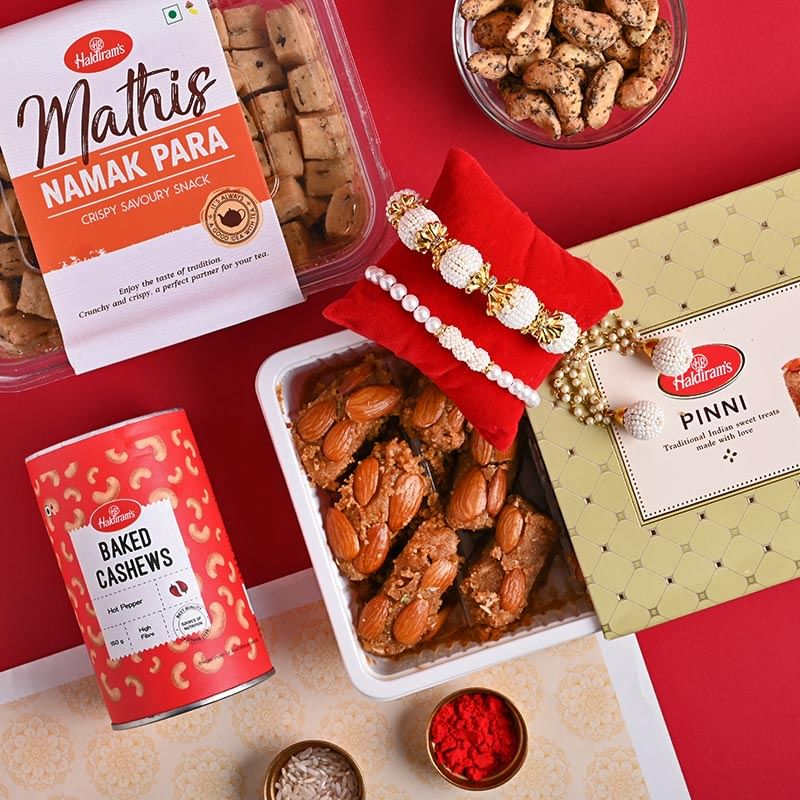 Buy Lumba Rakhi Online For Bhaiya bhabhiwith Sweets & Dry Fruits - Punjabi Pinni Baked Cashews N Namak Para with Bhaiya Bhabhi Pearls Rakhis